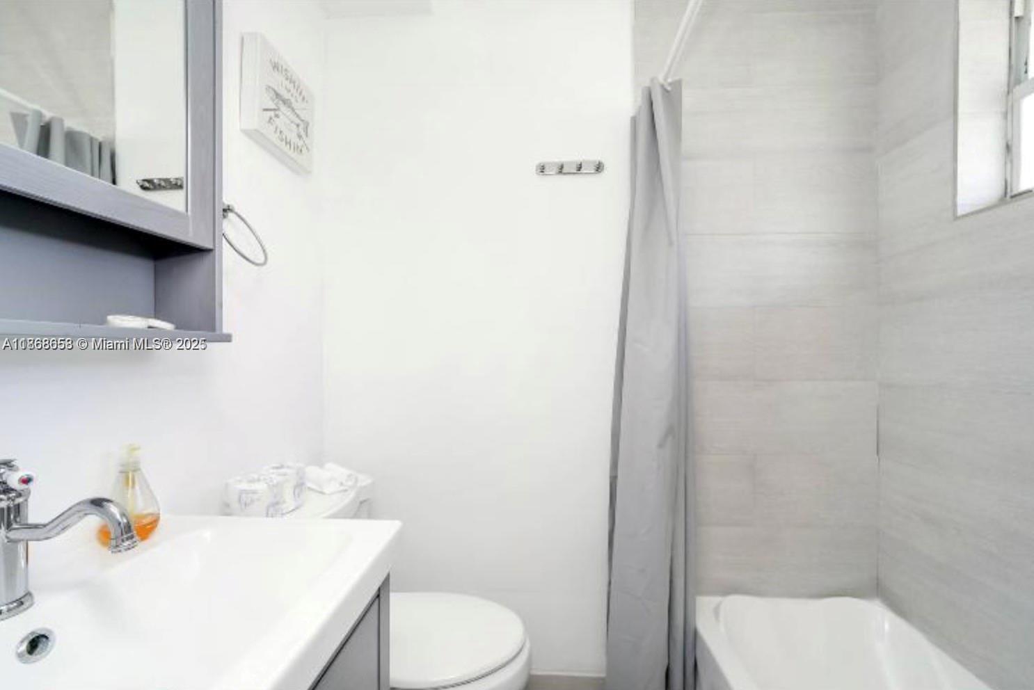 3030 Collins Avenue, Unit 4F Miami Beach, FL 33140 - Photo 7 of 24 a bathroom with a sink a toilet and shower curtain