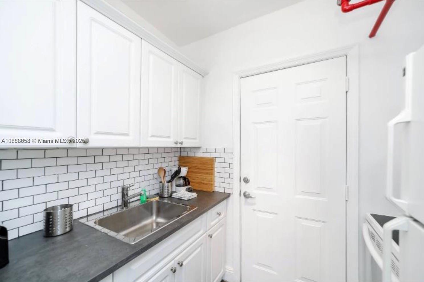 3030 Collins Avenue, Unit 4F Miami Beach, FL 33140 - Photo 8 of 24 a kitchen with a sink and cabinets