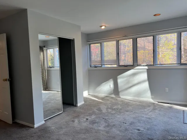 an empty room with large windows and a kitchen view