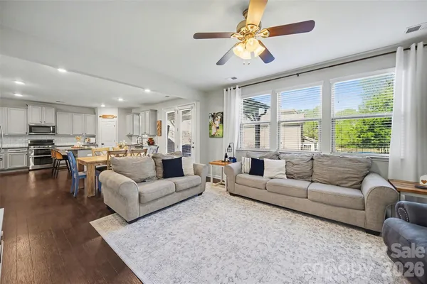 a living room with furniture kitchen view and a large window