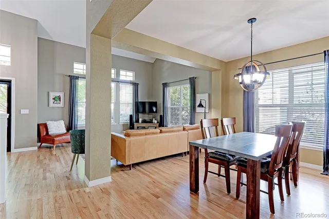 a dining room with furniture wooden floor a rug a potted plant and a chandelier