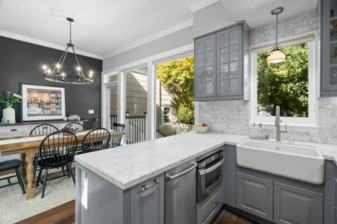 a kitchen with a stove a sink a center island and windows