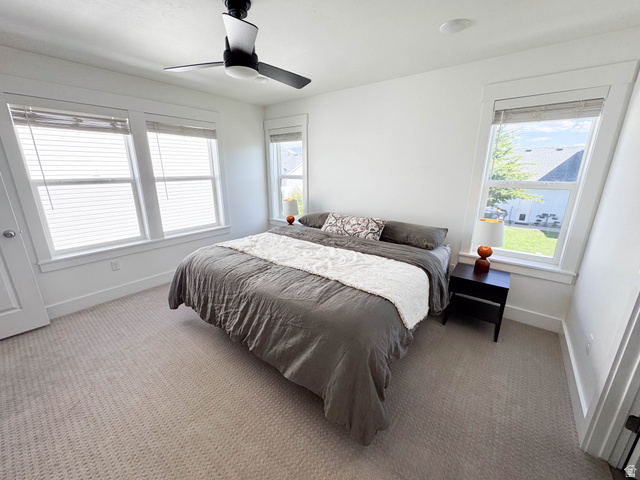 1486 West 2055th Street South Logan, UT 84339 - Photo 18 of 45 Bright bedroom featuring multiple large windows with white trim, wall-to-wall carpeting, and a ceiling fan with integrated lighting