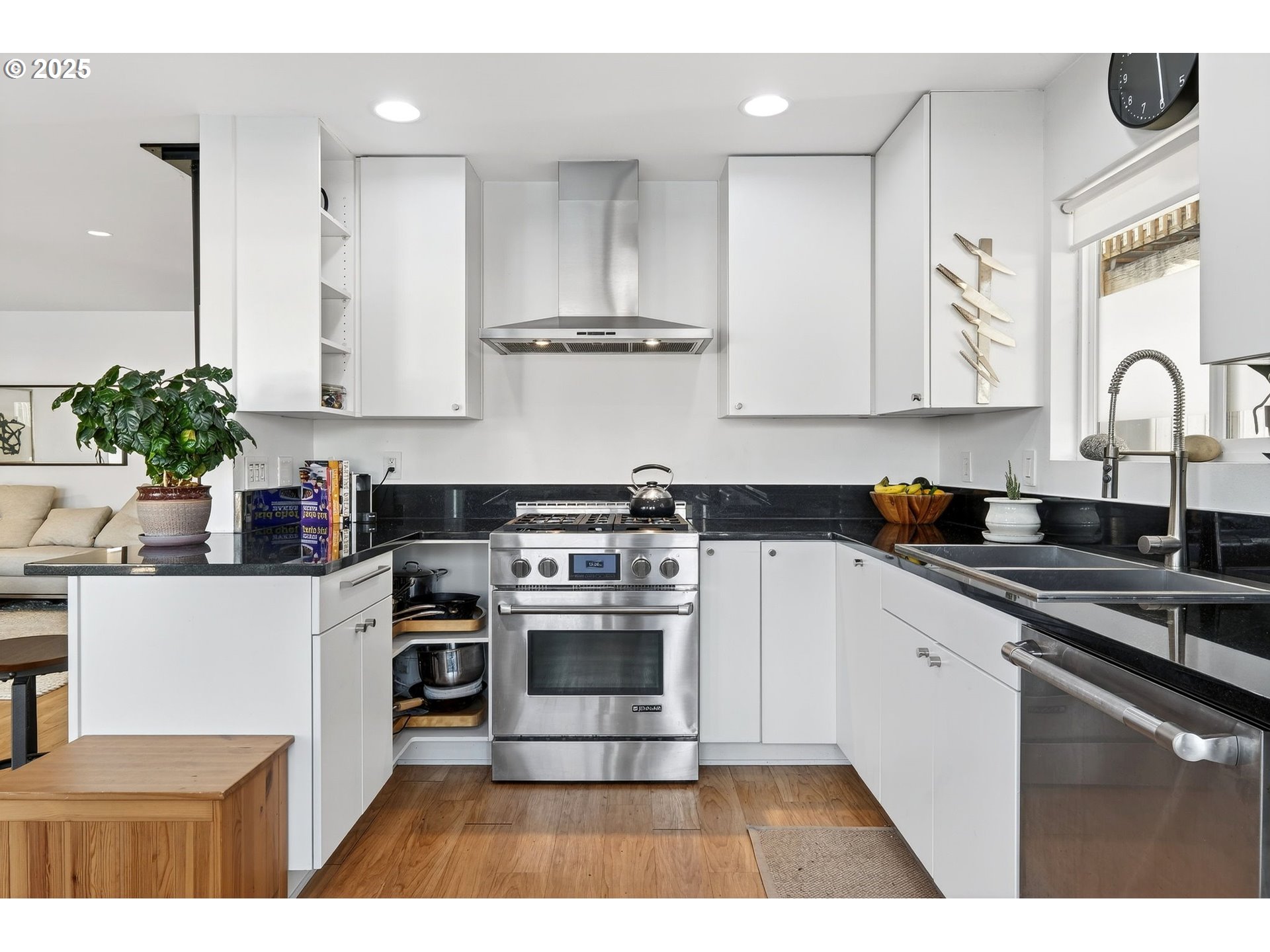 173 Northeast Bridgeton Road, Unit 13 Portland, OR 97211 - Photo 9 of 22 a kitchen with stainless steel appliances granite countertop a stove a sink dishwasher and white cabinets with wooden floor