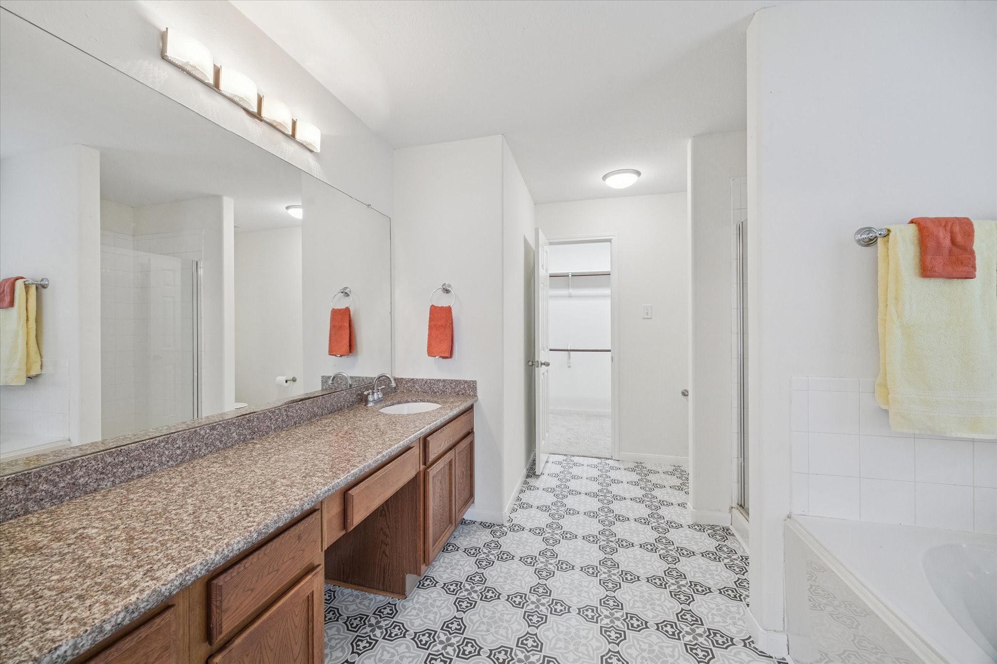 14102 Kinsbourne Lane Houston, TX 77014 - Photo 6 of 13 The on-suite primary bath features granite counter, new vinyl tile, stand-alone shower and separate garden tub. There is a large window in the tub area bringing in lots of natural light and dressed with an upholstered valance and blinds. Window treatments throughout the home can remain if the buyer desires.