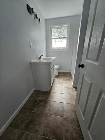a bathroom with a sink a toilet a window and vanity