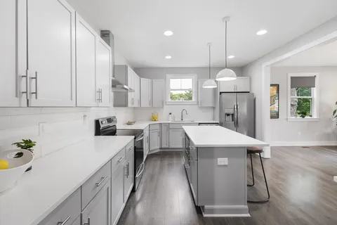 a kitchen with a sink a center island stainless steel appliances and cabinets