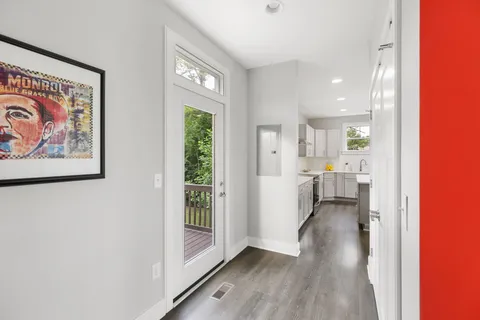 a view of a hallway with wooden floor and a bathroom