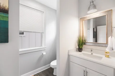 a bathroom with a granite countertop sink toilet and mirror