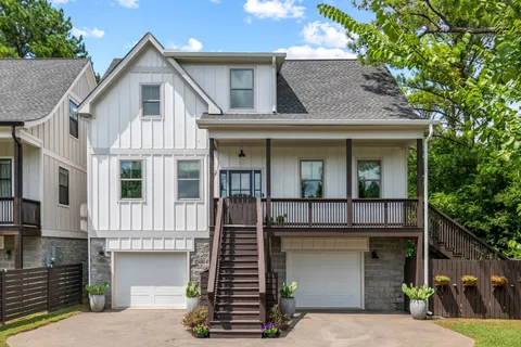 a view of a white house with large windows and a small yard