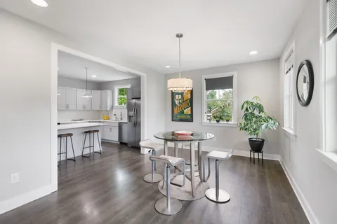 a view of a dining room and livingroom with furniture wooden floor a chandelier