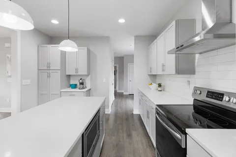 a kitchen with kitchen island a stove a sink a refrigerator and chairs