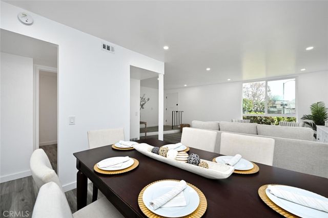 a living room with furniture and a dining table with wooden floor