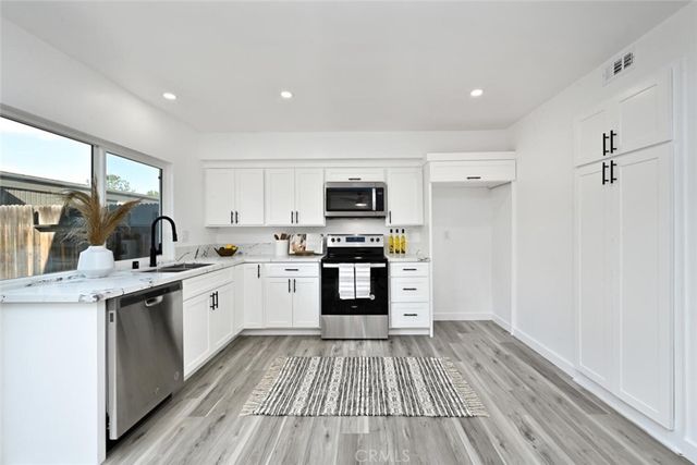 a kitchen with granite countertop wooden floors a sink and appliances