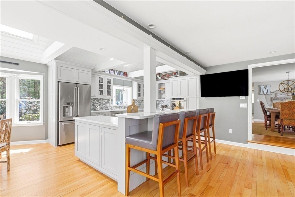 12 Salt Marsh Lane Wareham, MA 02571 - Photo 7 of 41 a kitchen with stainless steel appliances kitchen island granite countertop a stove a refrigerator a sink a dining table and chairs with wooden floor