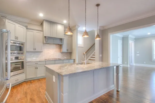 a kitchen with stainless steel appliances granite countertop a sink a stove and a wooden floors