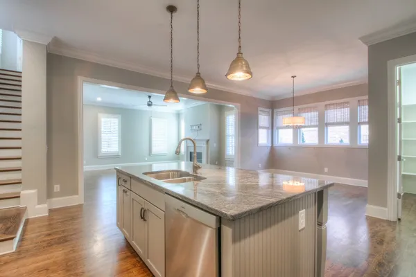 a kitchen with stainless steel appliances granite countertop a stove a sink a center island and wooden floor