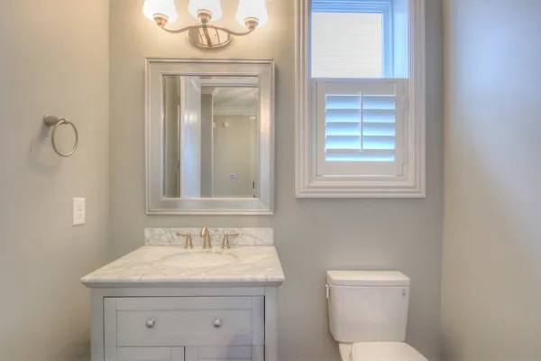 a bathroom with a granite countertop toilet a sink and a window