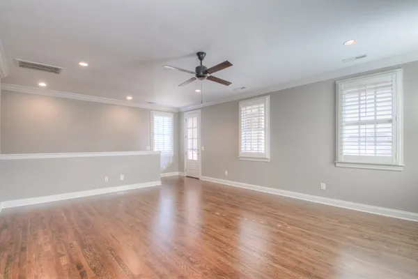 an empty room with wooden floor and windows