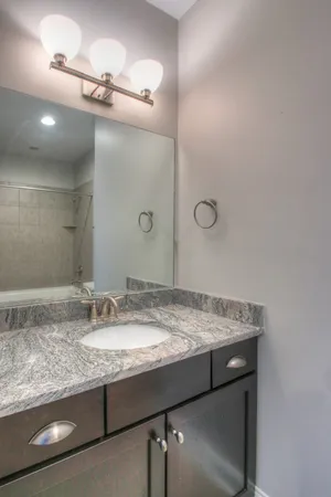 a bathroom with a granite countertop sink a mirror and shower