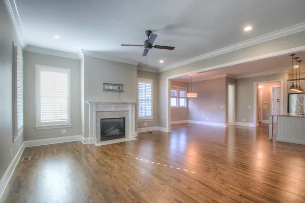an empty room with wooden floor fireplace and windows