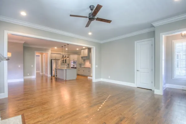 a view of an empty room and kitchen with a sink wooden floor and a window