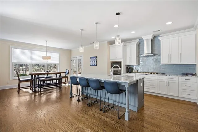 a kitchen with stainless steel appliances granite countertop a refrigerator a sink dishwasher a stove and white cabinets with wooden floor