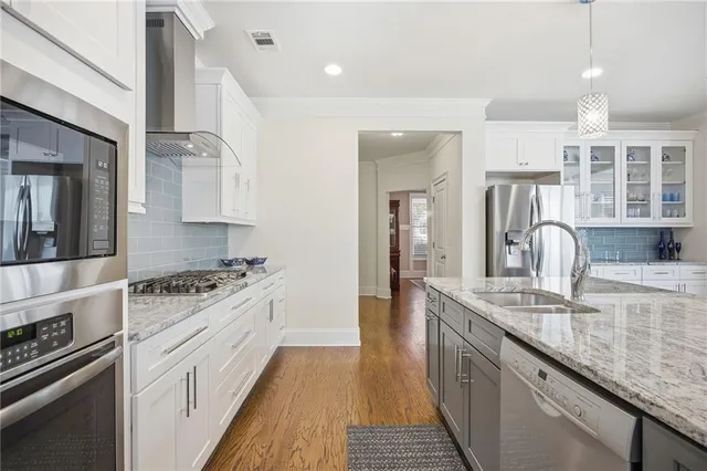 a kitchen with stainless steel appliances granite countertop a refrigerator a sink dishwasher a oven and a dining table with wooden floor