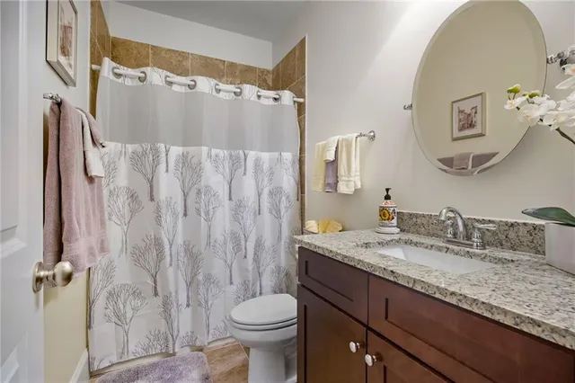 a bathroom with a granite countertop sink toilet a mirror and a window