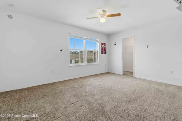 an empty room with windows and ceiling fan