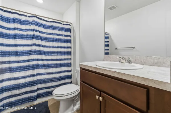 a bathroom with a granite countertop sink a toilet a mirror and shower curtain