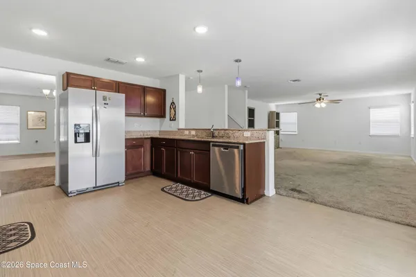 a kitchen with stainless steel appliances kitchen island granite countertop a refrigerator and a sink