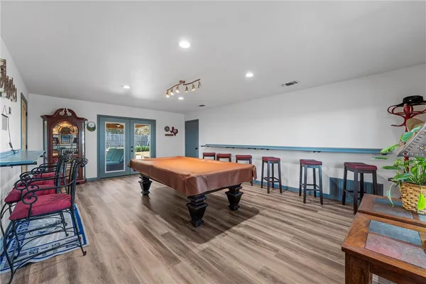 a spacious bedroom with a bed a table and chair with the wooden floor