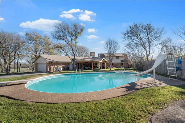 a view of a house with pool yard and trees