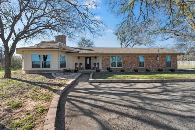 a view of a white house with a large tree