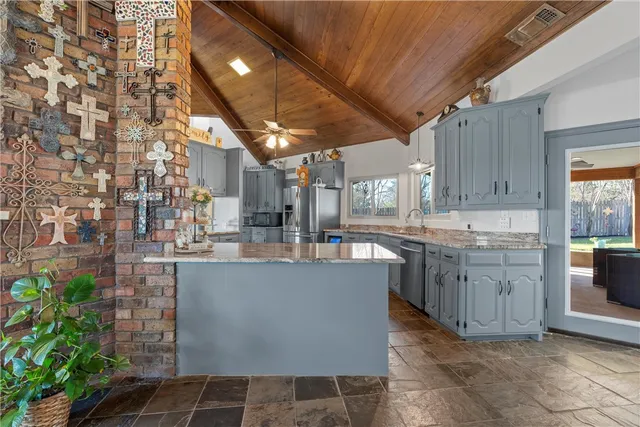 a kitchen with kitchen island granite countertop a sink a counter top space and cabinets