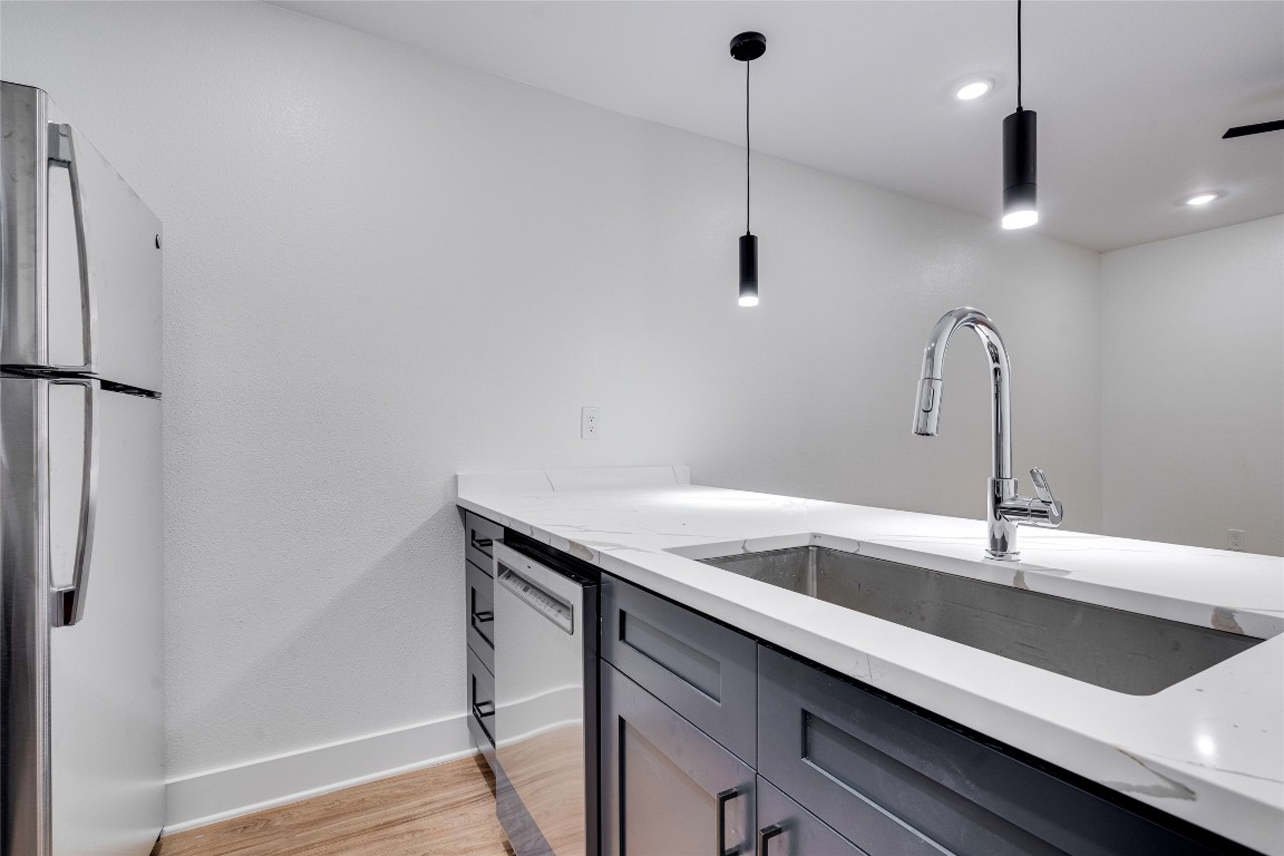 202 East 45th Street, Unit 202 Austin, TX 78751 - Photo 12 of 29 Kitchen with appliances with stainless steel finishes, decorative light fixtures, light stone counters, and light wood finished floors