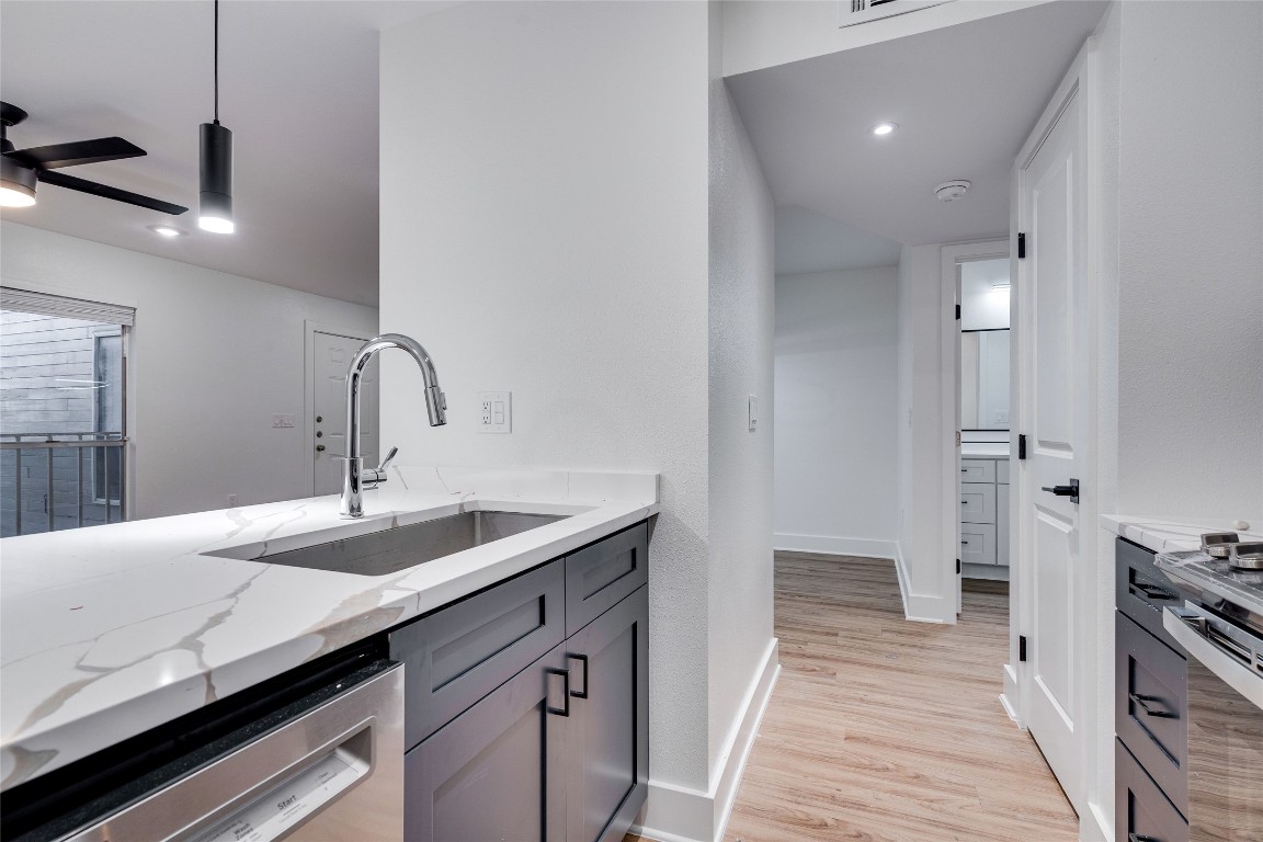 202 East 45th Street, Unit 202 Austin, TX 78751 - Photo 16 of 29 Kitchen with light stone countertops, stainless steel appliances, hanging light fixtures, light wood finished floors, and gray cabinetry