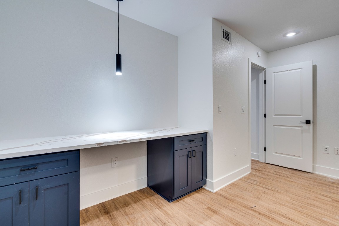 202 East 45th Street, Unit 202 Austin, TX 78751 - Photo 21 of 29 Kitchen with light wood-style flooring, hanging light fixtures, blue cabinetry, and light stone counters