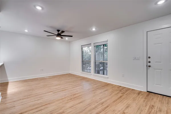 a view of an empty room with a window and wooden floor
