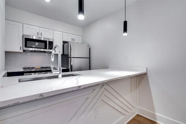 a kitchen with stainless steel appliances a refrigerator a stove a microwave and white cabinets