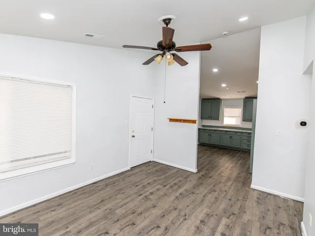 an empty room with wooden floor and ceiling fan