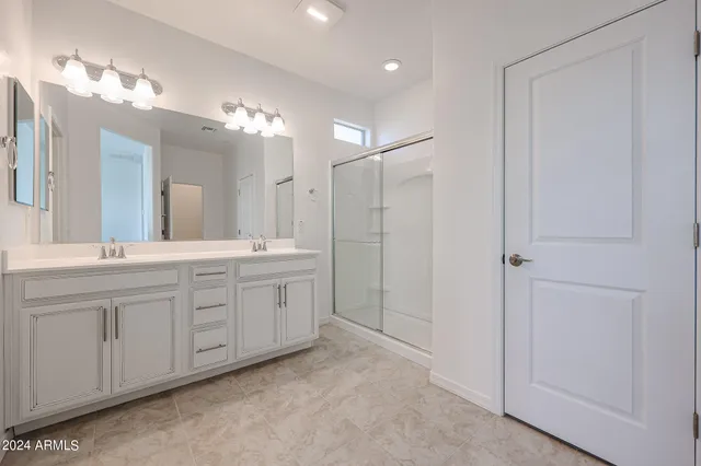 a spacious bathroom with a shower a sink and a mirror