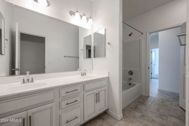 a spacious bathroom with double sink a mirror a shower and a bathtub