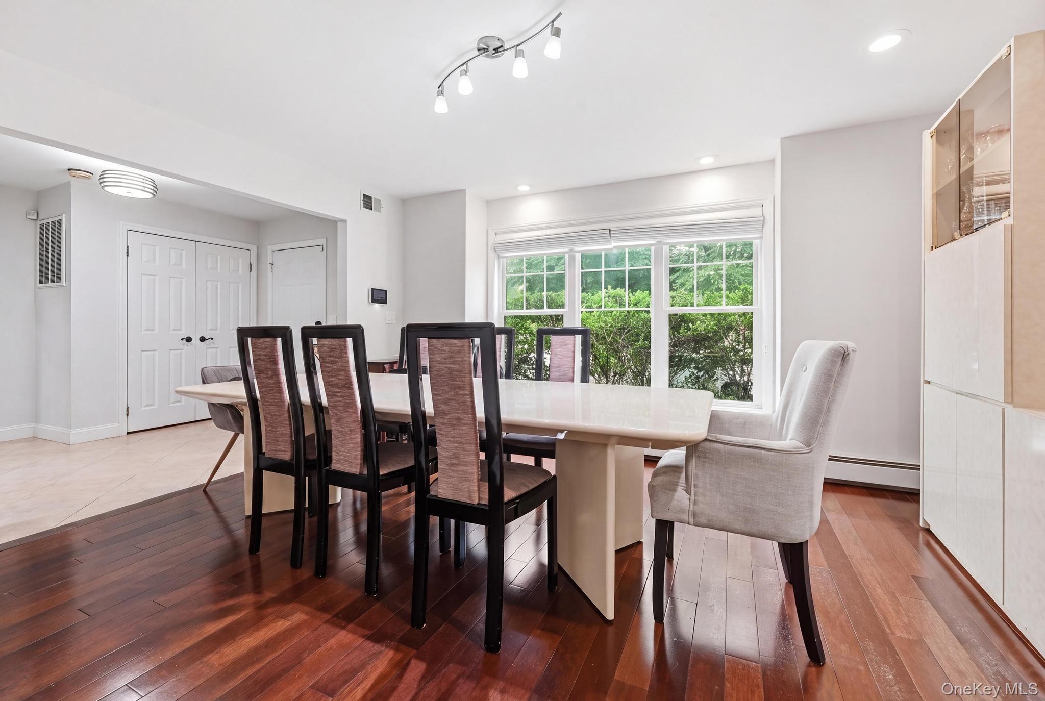 19 Sunset Road West Albertson, NY 11507 - Photo 5 of 24 Dining area featuring rich wood-finish flooring, a contemporary light fixture, and a large window offering exterior scenery