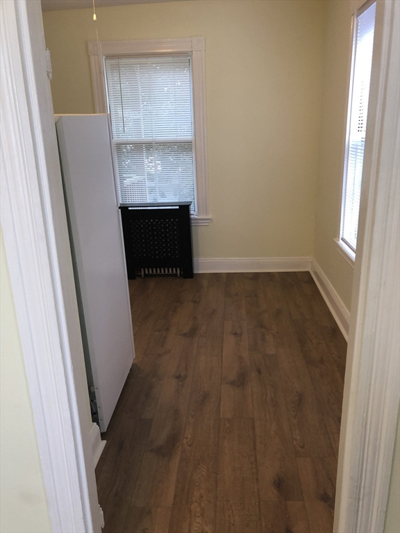 6 Rowley Street, Unit 1R Boston, MA 02122 - Photo 3 of 9 an empty room with wooden floor and windows
