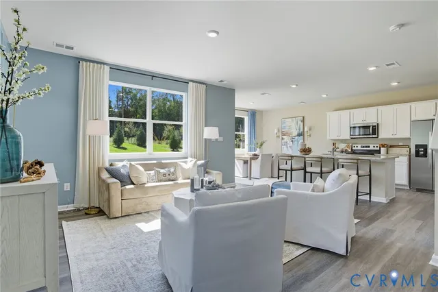 a living room with couches and kitchen view with wooden floor