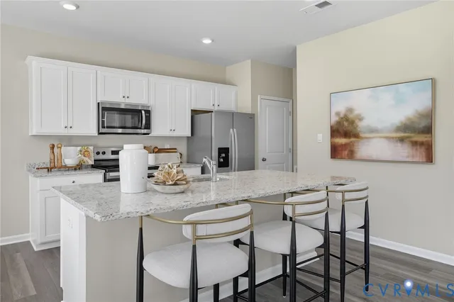 a kitchen with stainless steel appliances granite countertop a dining table chairs and a refrigerator