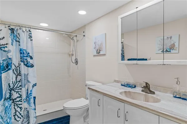 a bathroom with a granite countertop sink a toilet and shower