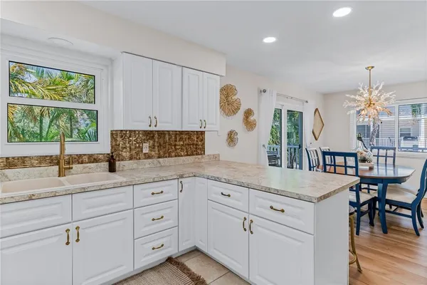 a kitchen with granite countertop white cabinets a stove a sink and a window